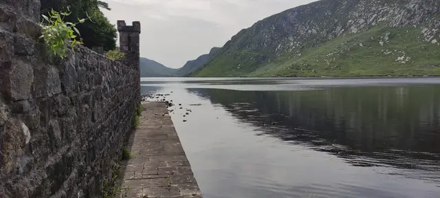 a stone wall next to a body of water with a stone walkway