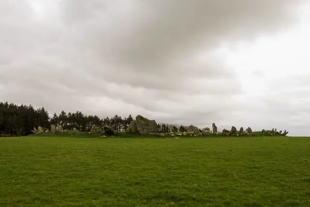 a grassy field with rocks in the distance