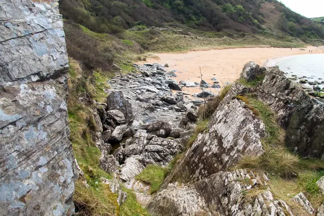 a rocky beach with a body of water in the background