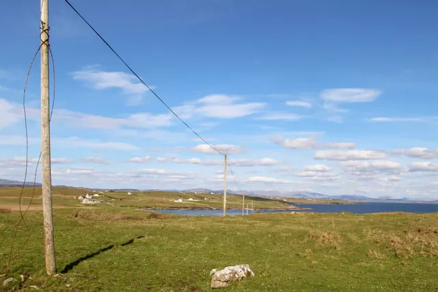 a field with power lines with Codrington Wind Farm in the background