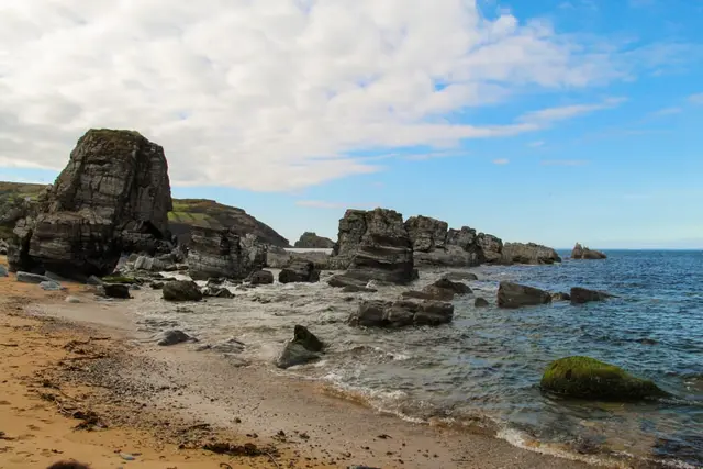 a rocky beach with a body of water in the background