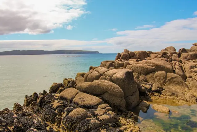 a rocky beach with a body of water in the background