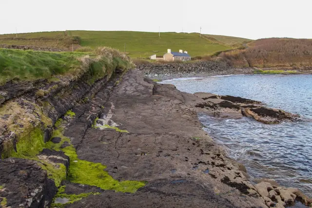 a rocky beach with a house in the background