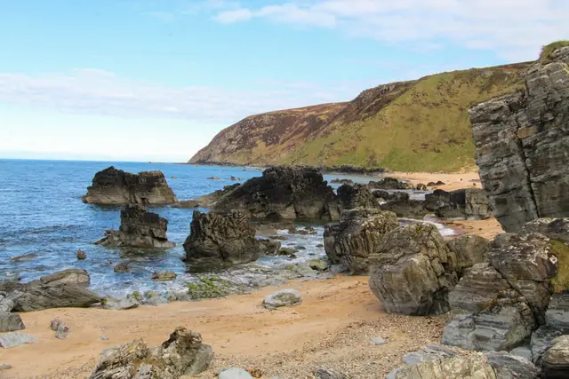 a rocky beach with a body of water in the background