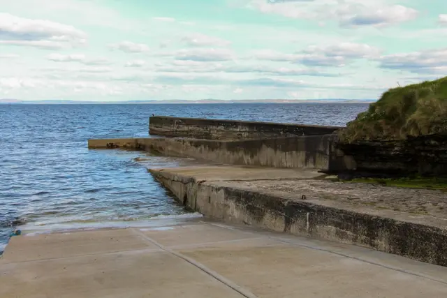 a stone wall next to a body of water