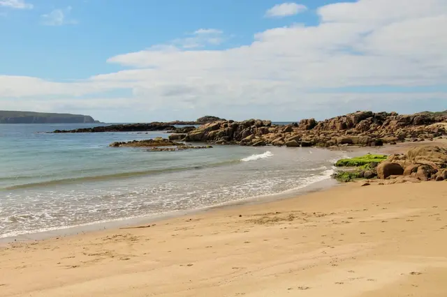 a sandy beach with rocks and water