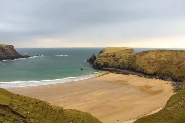 a beach with a body of water and cliffs