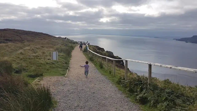 a group of people walking on a path by a body of water