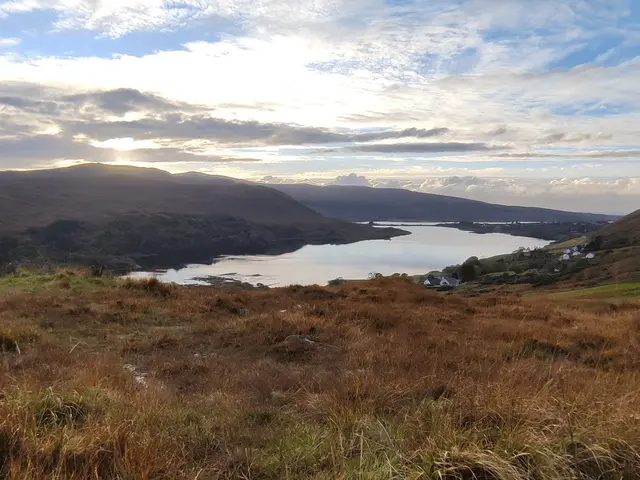 a lake surrounded by grass and hills