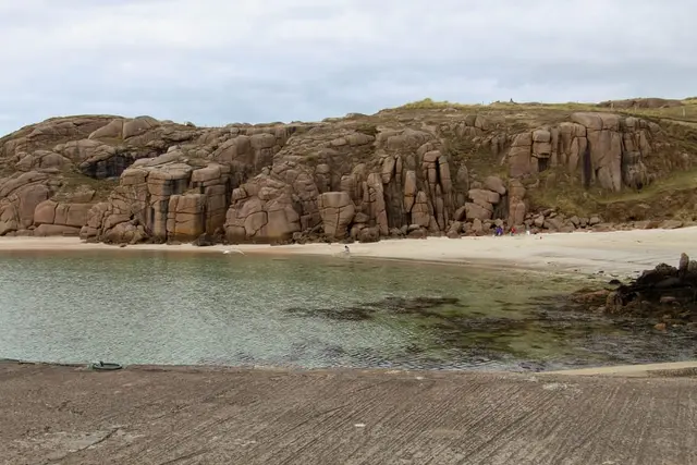 a rocky beach with a body of water and a rocky cliff