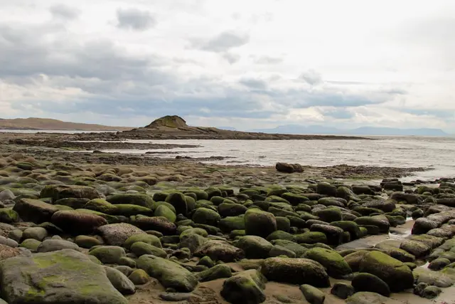 a rocky beach with a body of water in the background