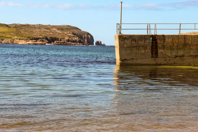 a body of water with a concrete wall and a bridge in the background
