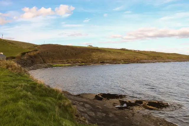 a body of water with grass and hills around it