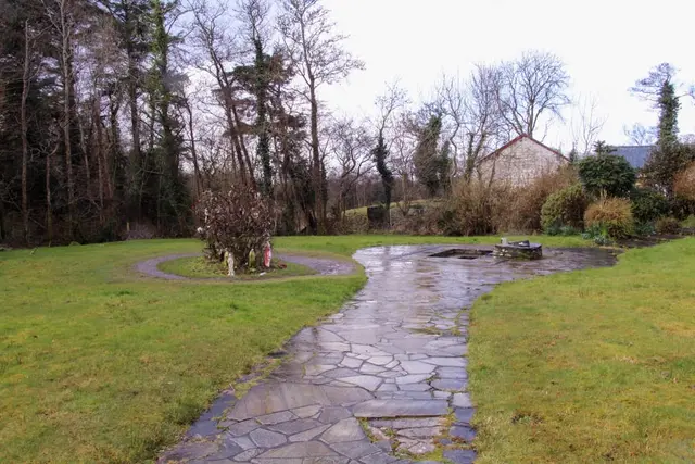 a stone pathway with grass and trees