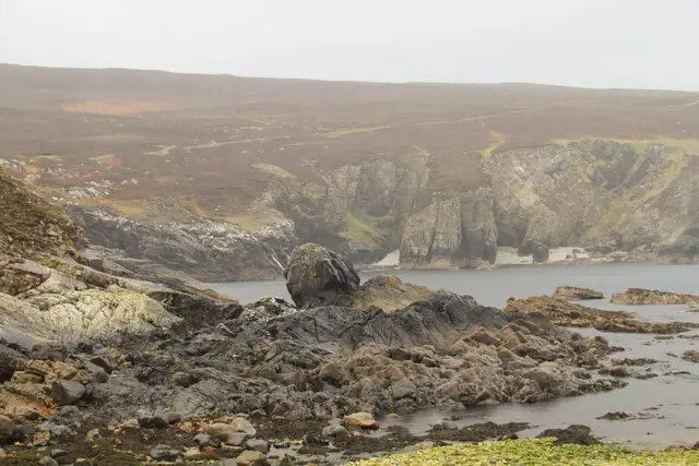 a rocky landscape with a body of water and a large rocky cliff