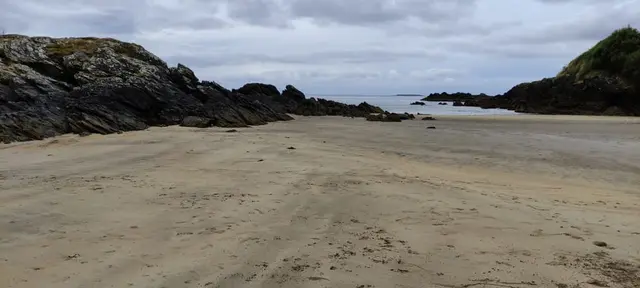 a sandy beach with rocks and water
