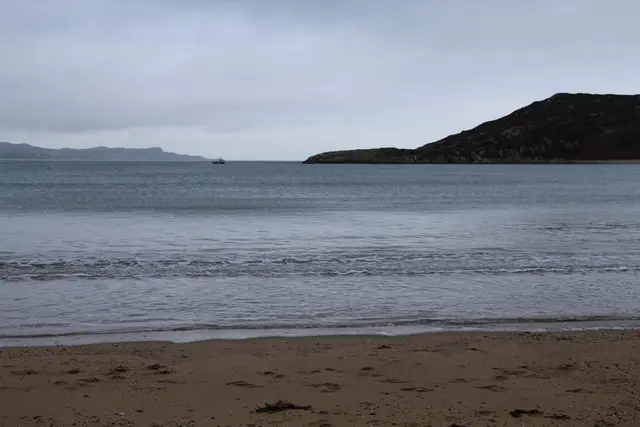 a beach with a body of water and hills in the background
