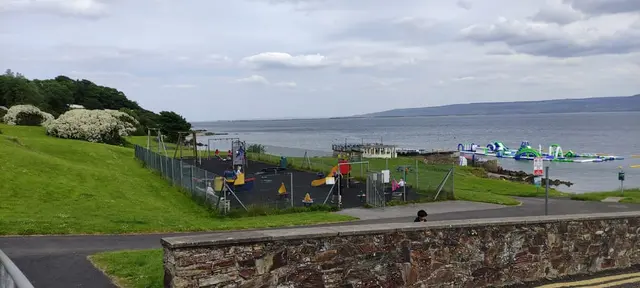 a park with a fence and a body of water in the background