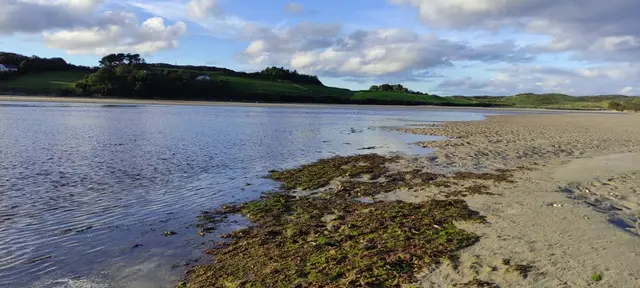 a beach with a body of water and hills in the background
