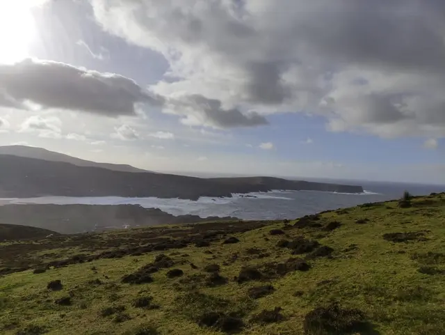 Glencolmcille view, a grassy area with water and hills in the background