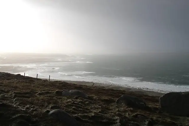 a rocky beach with a body of water in the background