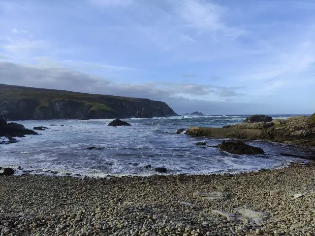 An Port, a rocky beach with a body of water and hills in the background