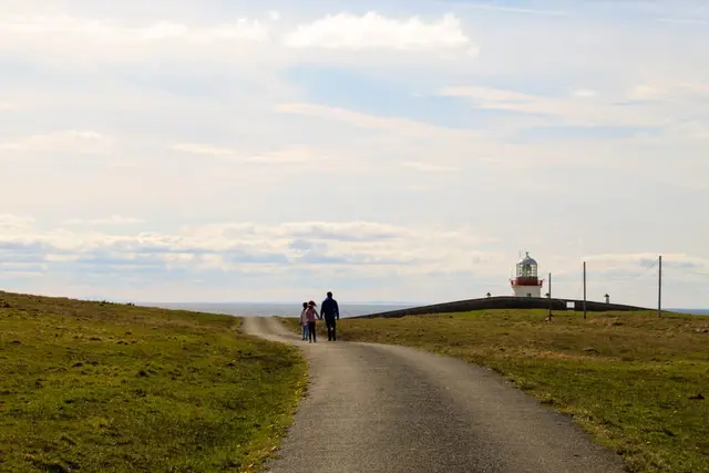 a group of people walking on a path by a lighthouse