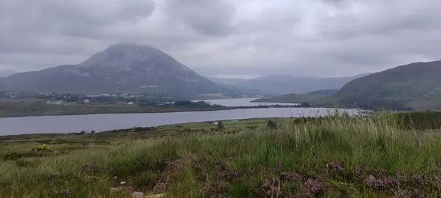 a body of water with grass and hills around it