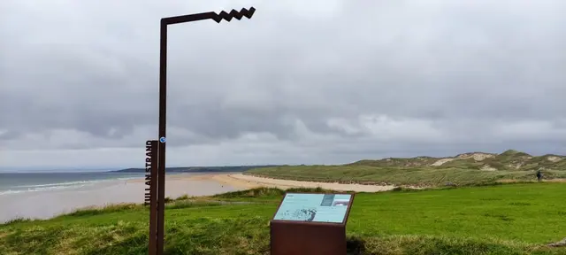 a sign on a grassy area by a beach